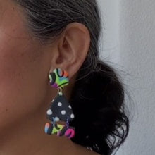 Load image into Gallery viewer, A video still of Vicky from Pink Lime Mango modelling handcrafted earrings for size reference. Bright, bold and colourful Flower Moth Bumps earrings made in Bristol UK