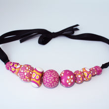 Load image into Gallery viewer, Measurements: each bead is between 1.5cm to 3cm Each design is exclusively unique and one of a kind! Finished with a lovely black ribbon tie so you can adjust the necklace length. A bold and colourful statement necklace featuring eleven different millefiori style handmade beads.  The colours are purple, pink, white and mustard yellow.