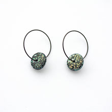 Load image into Gallery viewer, Black glitter sparkly discs on stainless steel black hoops! These feature iridescent glitter which changes between blue, gold and green. Unique and one of a kind!