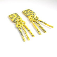 Load image into Gallery viewer, These are the beautiful Hope Dangles. The top rectangular pieces have a unique yellow and grey pattern with a silver plated stud top fixing at the back. The middle section swirls with both colours and then is completed with a delicate triple tube fringe.