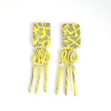 Load image into Gallery viewer, These are the beautiful Hope Dangles. The top rectangular pieces have a unique yellow and grey pattern with a silver plated stud top fixing at the back. The middle section swirls with both colours and then is completed with a delicate triple tube fringe.
