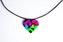 Load image into Gallery viewer, The Status Heart Pendant has squiggles of neon purple, neon pink, neon blue, neon yellow and neon green against a black background. With a waxed black cotton cord.