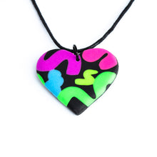 Load image into Gallery viewer, The heart pendant has squiggles of neon purple, neon pink, neon blue, neon yellow and neon green against a black background. Close up with a waxed black cotton cord.