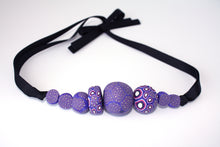 Load image into Gallery viewer, Measurements: each bead is between 1.5cm to 3.5cm Each design is exclusively unique and one of a kind! Finished with a lovely black ribbon tie so you can adjust the necklace length. A beautiful, bold and colourful statement necklace featuring eight different millefiori style handmade beads. The colours are purple, pink and white.