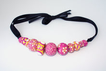 Load image into Gallery viewer, Measurements: each bead is between 1.5cm to 3cm Each design is exclusively unique and one of a kind! Finished with a lovely black ribbon tie so you can adjust the necklace length. A bold and colourful statement necklace featuring eleven different millefiori style handmade beads. The colours are purple, pink, white and mustard yellow.