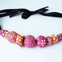 Load image into Gallery viewer, Measurements: each bead is between 1.5cm to 3cm Each design is exclusively unique and one of a kind! Finished with a lovely black ribbon tie so you can adjust the necklace length. A bold and colourful statement necklace featuring eleven different millefiori style handmade beads. The colours are purple, pink, white and mustard yellow.