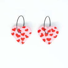Load image into Gallery viewer, Gratitude Hoops - handcrafted light pink hearts with a small red hearts texture laid across the surface. Attached with black hypoallergenic stainless steel hoops.