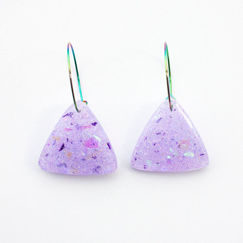 Sparkly lilac triangular earrings from the Under the Sea resin collection. Beautiful layers of fine iridescent glitter, colour shifting aurora flakes and tiny pieces of metallic purple foil. A unique design that has been complimented with multicoloured rainbow hoops!