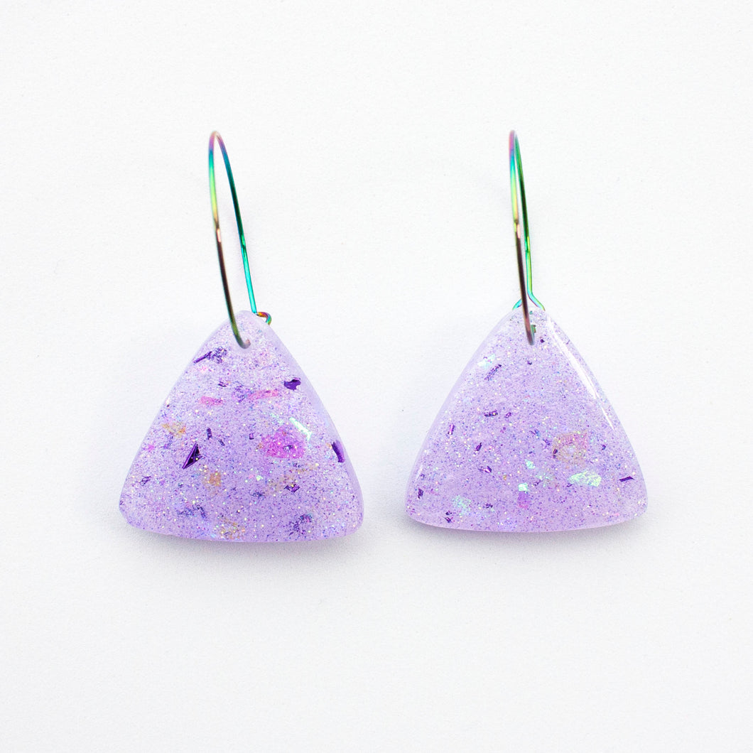 Sparkly lilac triangular earrings from the Under the Sea resin collection. Beautiful layers of fine iridescent glitter, colour shifting aurora flakes and tiny pieces of metallic purple foil. A unique design that has been complimented with multicoloured rainbow hoops!