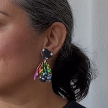 Load image into Gallery viewer, A video still of Vicky from Pink Lime Mango modelling handcrafted earrings for size reference. Bright, bold and colourful Neon Butterfly Switch earrings made in Bristol UK
