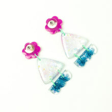 Load image into Gallery viewer, Vibrant handcrafted resin earrings with a pink flower top, the middle parts are frosted white triangles with pink cloud patterns and a sprinkling of electric blue glitter. The base element has sparkly lilac flowers perfectly placed above a layer of electric blue glitter. Complimented with mint green jump rings. Earrings backs are shown in the photo.