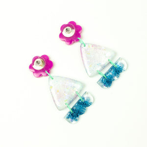 Vibrant handcrafted resin earrings with a pink flower top, the middle parts are frosted white triangles with pink cloud patterns and a sprinkling of electric blue glitter. The base element has sparkly lilac flowers perfectly placed above a layer of electric blue glitter. Complimented with mint green jump rings. Earrings backs are shown in the photo.