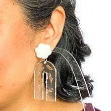 Load image into Gallery viewer, Handcrafted earrings with arches of clear resin containing sea lavender flowers. The stud top is a white flower containing the most wonderful colourful changing aurora flakes of glitter. Model shot.