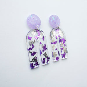 Gorgeous handcrafted resin earrings with round glittery lilac stud tops! These beautiful arch dangle earrings are decorated with delicate pieces of silver and purple foils. Side view.