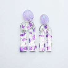 Load image into Gallery viewer, Gorgeous handcrafted resin earrings with round glittery lilac stud tops! These beautiful arch dangle earrings are decorated with delicate pieces of silver and purple foils. Side view.