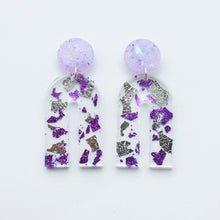 Load image into Gallery viewer, Gorgeous handcrafted resin earrings with round glittery lilac stud tops! These beautiful arch dangle earrings are decorated with delicate pieces of silver and purple foils.

