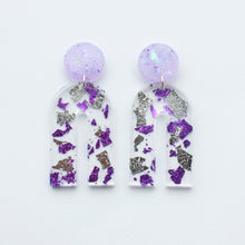 Load image into Gallery viewer, Gorgeous handcrafted resin earrings with round glittery lilac stud tops! These beautiful arch dangle earrings are decorated with delicate pieces of silver and purple foils.