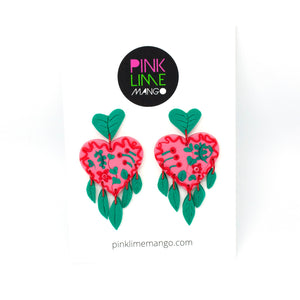 The Green Planet earrings by Pink Lime Mango. The stud tops are green leaves that are also abstract heart shapes. The pink heart in the middle is decorated with red and green swirls, minitaure leaves and flowers. The earrings have a delicate fringe of hand cut leaves and they hang beautifully!