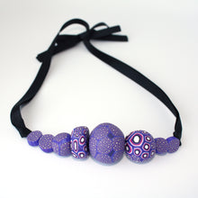 Load image into Gallery viewer, Measurements: each bead is between 1.5cm to 3.5cm Each design is exclusively unique and one of a kind! Finished with a lovely black ribbon tie so you can adjust the necklace length. A beautiful, bold and colourful statement necklace featuring eight different millefiori style handmade beads.  The colours are purple, pink and white.
