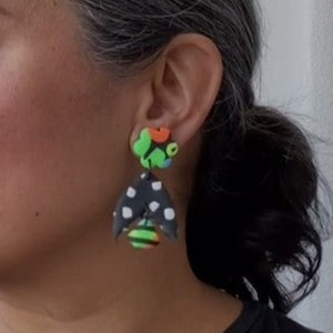 A video still of Vicky from Pink Lime Mango modelling handcrafted Neon Flower Batwing earrings for size reference. Bright, bold and colourful earrings made in Bristol UK