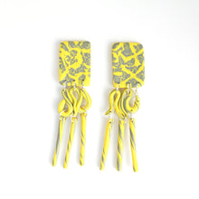 Load image into Gallery viewer, These are the beautiful Hope Dangles. The top rectangular pieces have a unique yellow and grey pattern with a silver plated stud top fixing at the back. The middle section swirls with both colours and then is completed with a delicate triple tube fringe. 
