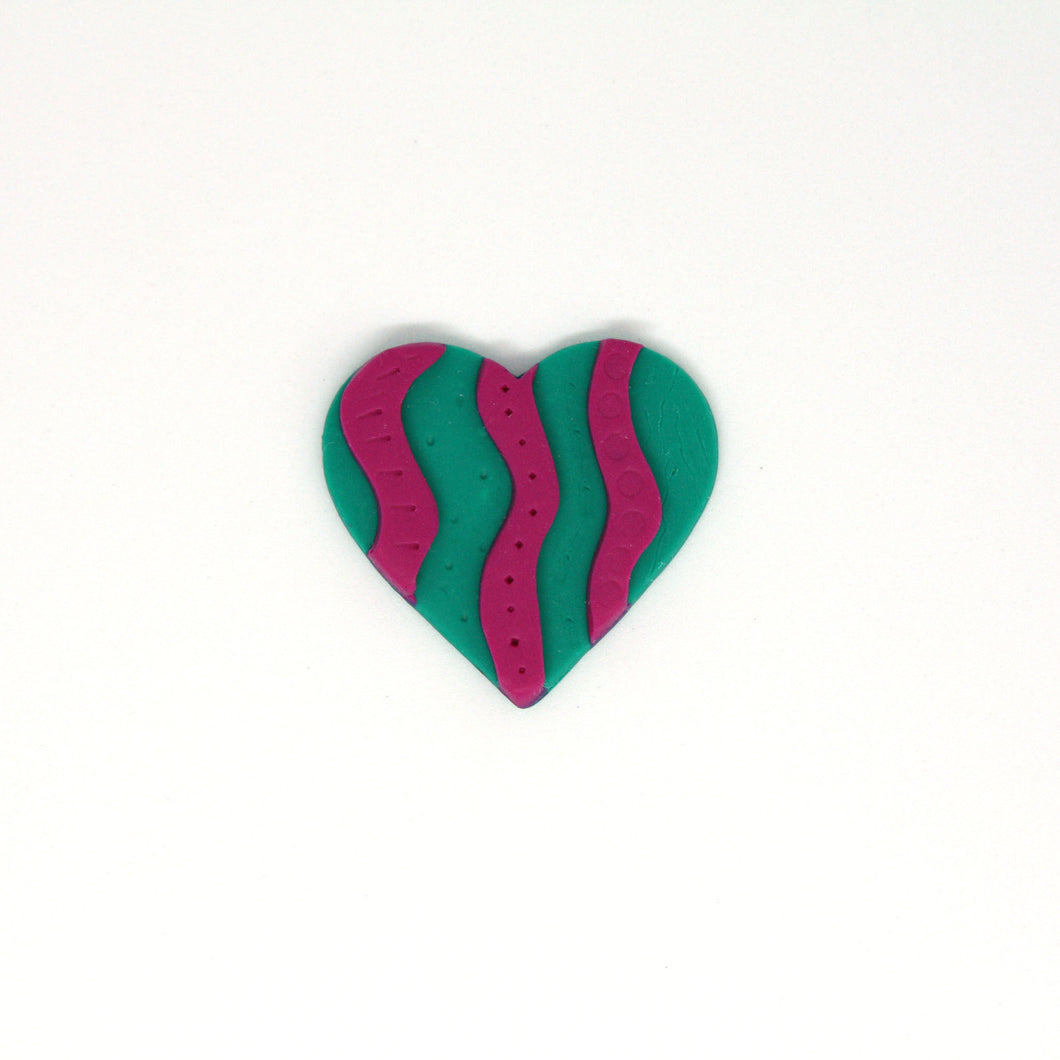 A colourful piece of wearable art! A vibrant green brooch with a raised pink squiggle pattern! Featuring intricate texturing done by hand!