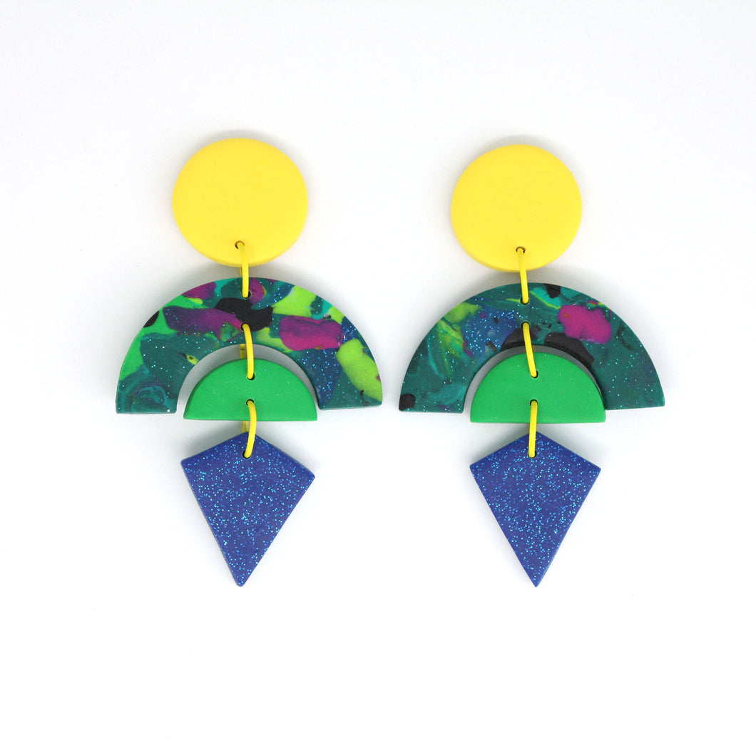 Beacon, a stunning pair of statement earrings, in the following layers, a vibrant yellow circle stud top, marbled glitter arch in deep green with multicoloured swirls encasing a bright green semi circle and a diamond shaped blue glitter piece at the bottom. Finished with a lovely detail - gorgeous yellow jump rings!