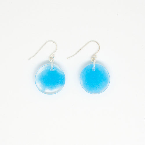 Blue Drops earrings have a cloudlike suspension of blue pigment floating in clear resin. The circular discs of resin are handcrafted. The earring hooks are made of sterling silver.