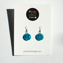 Load image into Gallery viewer, A stunning blue colour in these beautiful resin earrings! Oceans Blue Circle Drops feature chunky aqua eco-glitter and electric blue mica power. Shown with a Pink Lime Mango backing card.
