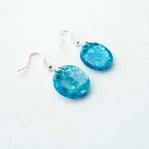 A stunning blue colour in these beautiful resin earrings! Oceans Blue Circle Drops feature chunky aqua eco-glitter and electric blue mica power. Side view.