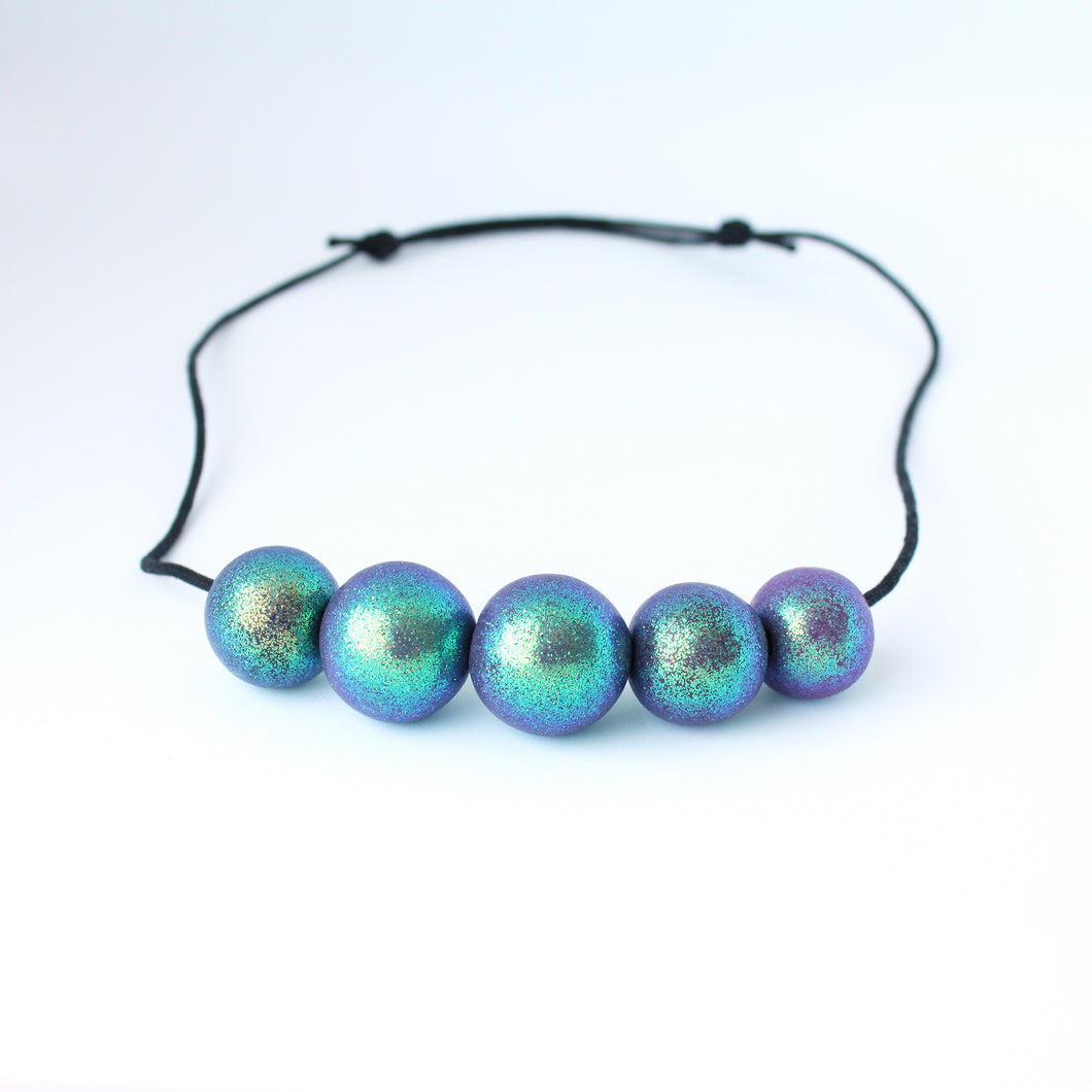 Measurements: each bead is approx 2.5cm Each design is exclusively unique! Featuring an adjustable waxed cotton cord An absolutely stunning iridescent 5 beaded necklace with purple, green and blue tones. These dazzling colours change with movement! Only one necklace available in this style!