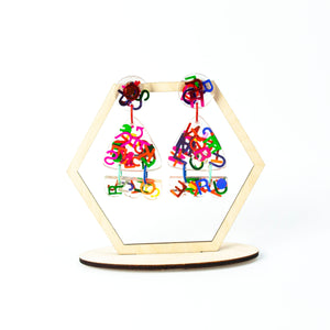 Handcrafted clear resin earrings decorated with multi-coloured foil letters! On a hexagonal earring display stand made by not a jewellery box
