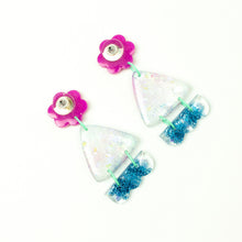 Load image into Gallery viewer, Vibrant handcrafted resin earrings with a pink flower top, the middle parts are frosted white triangles with pink cloud patterns and a sprinkling of electric blue glitter. The base element has sparkly lilac flowers perfectly placed above a layer of electric blue glitter. Complimented with mint green jump rings. Earrings backs are shown in the photo.
