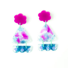 Load image into Gallery viewer, Vibrant handcrafted resin earrings with a pink flower top, the middle parts are frosted white triangles with pink cloud patterns and a sprinkling of electric blue glitter. The base element has sparkly lilac flowers perfectly placed above a layer of electric blue glitter. Complimented with mint green jump rings. Image shows the fronts of the earrings.
