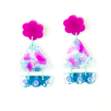 Load image into Gallery viewer, Vibrant handcrafted resin earrings with a pink flower top, the middle parts are frosted white triangles with pink cloud patterns and a sprinkling of electric blue glitter. The base element has sparkly lilac flowers perfectly placed above a layer of electric blue glitter. Complimented with mint green jump rings.
