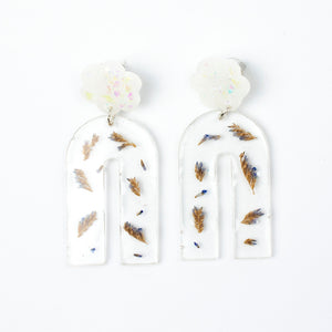 Handcrafted earrings with arches of clear resin containing sea lavender flowers. The stud top is a white flower containing the most wonderful colourful changing aurora flakes of glitter.