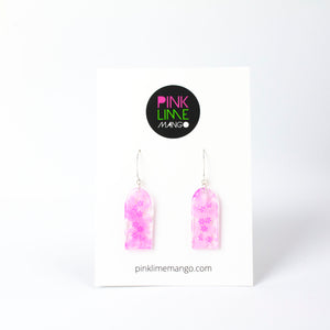 Delicate arches of clear resin with bursts of pale pink and tiny shimmery flower sequins. The unique V shaped earring hooks are made of sterling silver. On a Pink Lime Mango backing card.