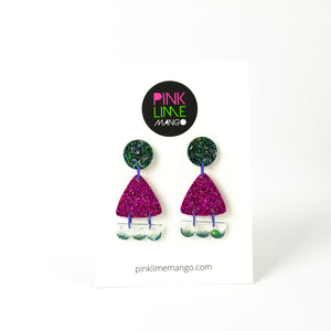 Earrings displayed on a Pink Lime Mango backing card. Handcrafted resin earrings decorated with teal blue and purple glitter. The round stud top has a been jam packed with gorgeous sparkly blue and green glitter. The middle triangle piece is fabulously purple and glittery! The three bumps piece at the bottom has clear resin with teal glitter edging.
