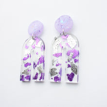 Load image into Gallery viewer, Gorgeous handcrafted resin earrings with round glittery lilac stud tops! These beautiful arch dangle earrings are decorated with delicate pieces of silver and purple foils. Side view.
