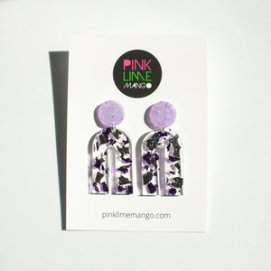 Gorgeous handcrafted resin earrings with round glittery lilac stud tops! These beautiful arch dangle earrings are decorated with delicate pieces of silver and purple foils. Pictured with a Pink Lime Mango earring backing card.